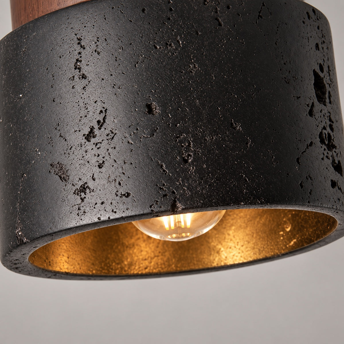 Detail van de zwarte natuursteen en warme binnenzijde van de Basalt plafondlamp