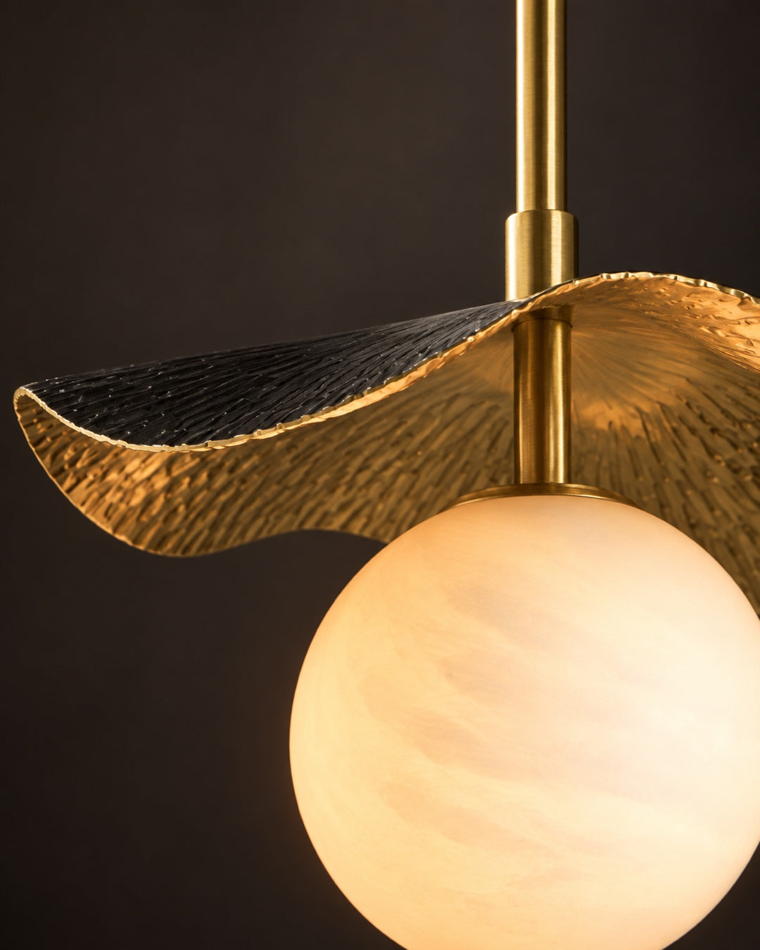 Close-up van de Fold Globe hanglamp met zwart oppervlak, gehamerd messing en albasten globe